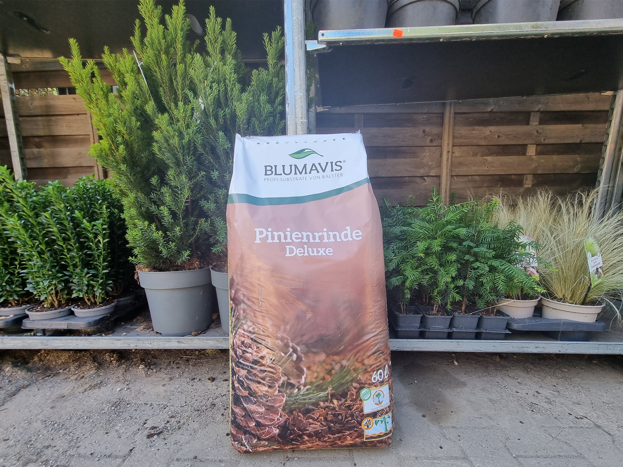 60 Liter Sack Pinienrinde vor grünen Pflanzen auf dem Betriebshof Brümmer.