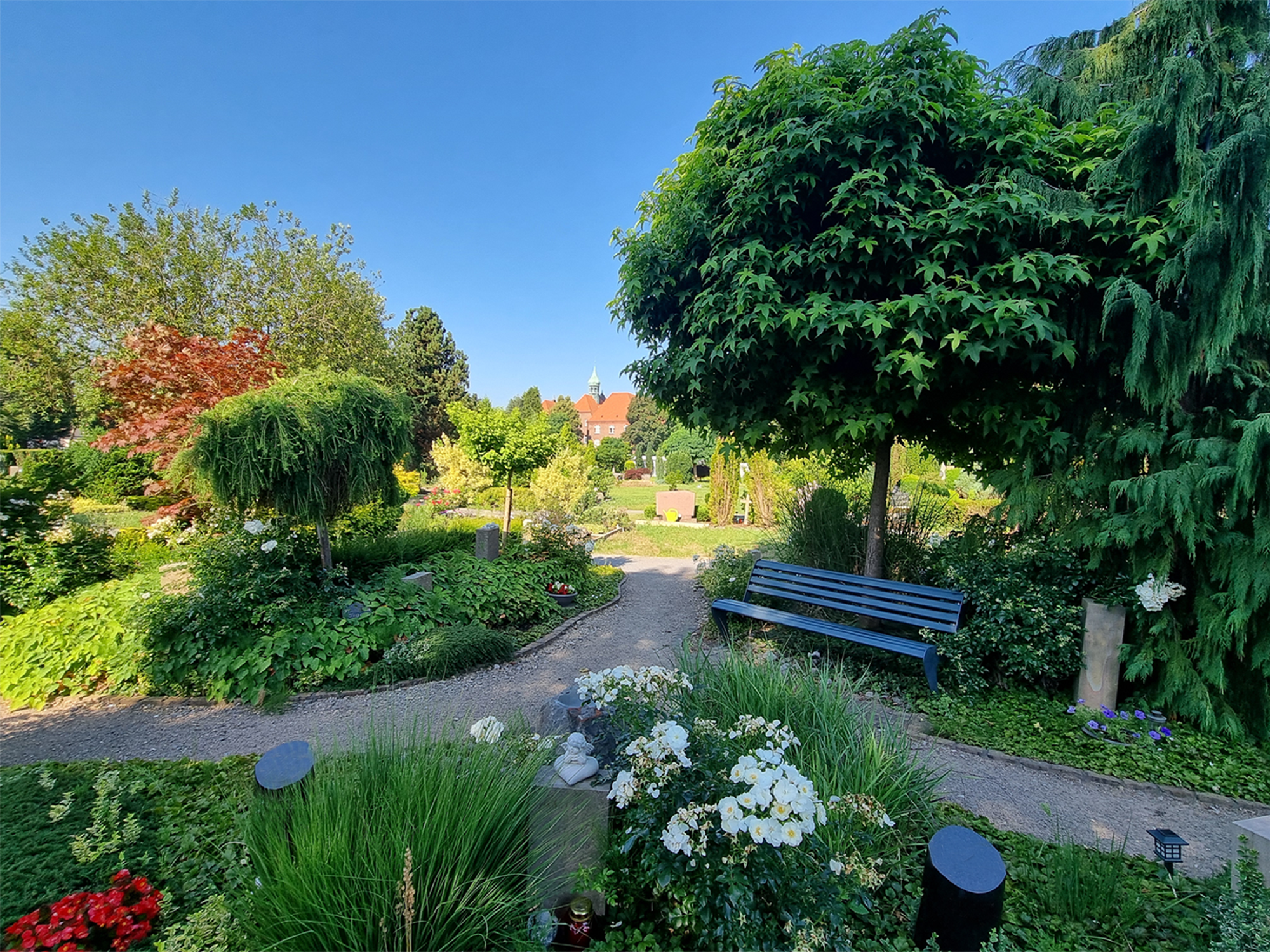 "Garten des Gedenkens" mit Urnengräbern, geschwungen Wegen, Bank und Bäumen.