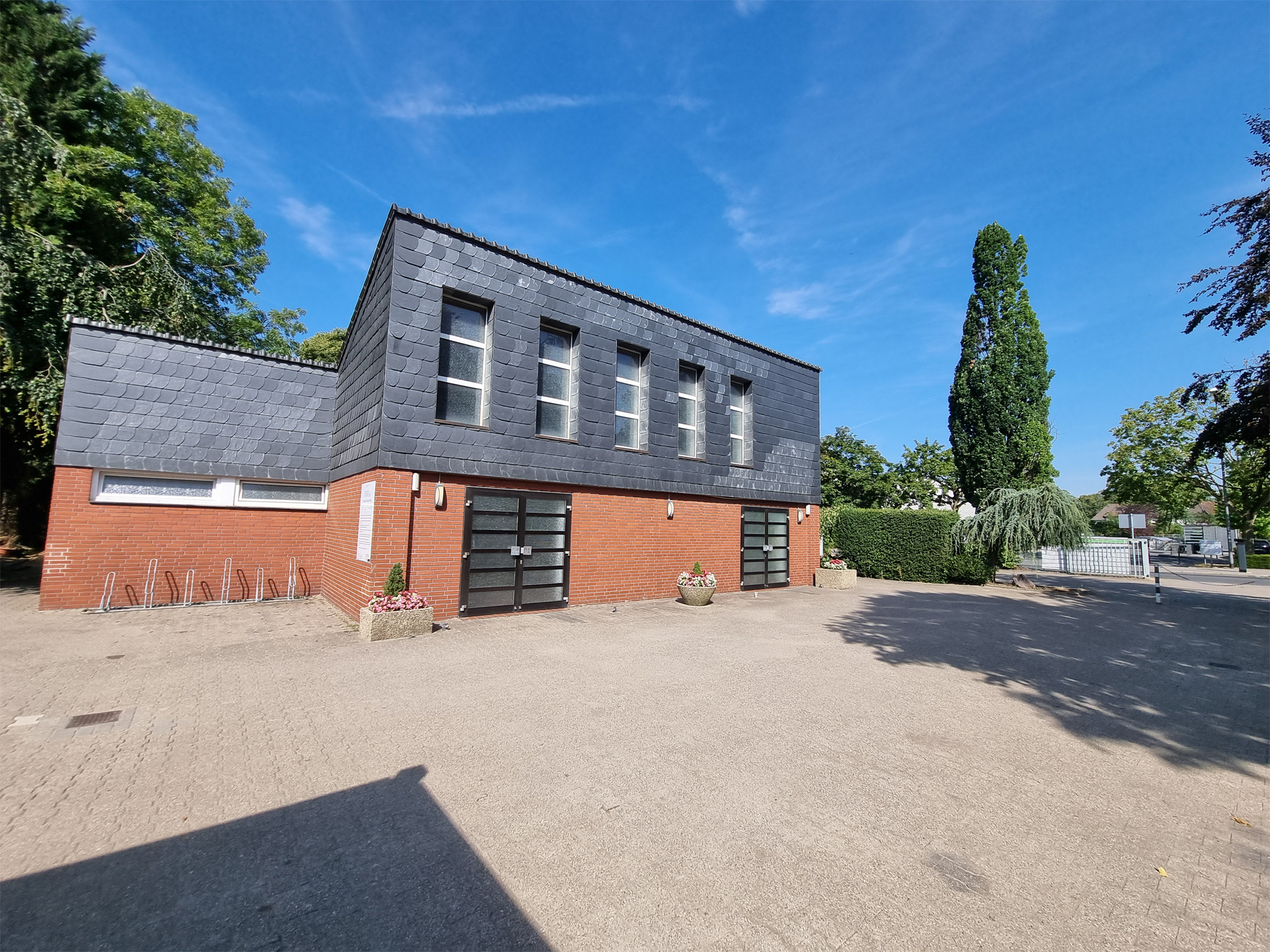 Trauerhalle des Evangelischen Friedhofs Wanne-Mitte mit Vorplatz und Parkplatz.