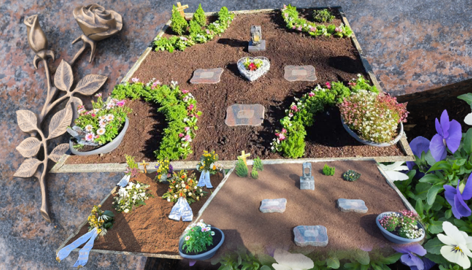 Frisch bepflanzte Ruhestätte mit Randbepflanzung, Blumen und Pflanzschalen.
